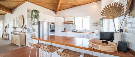 Een moderne keuken met een houten kookeiland, barstoelen en een grote ventilator.