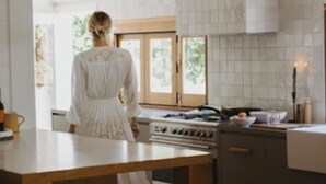 Une cuisine moderne avec un îlot central, des tabourets en bois et un luminaire suspendu.