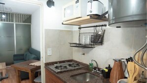 Cuina compacta amb fogó de gas, un rentaplat i microones. Zona de menjador amb taula i cadires.