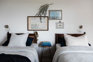 A hotel room with two beds, a small table with books, and wall-mounted artwork. - Seaside surf haven, pup friendly - Seafarers Lodge (Middleton)