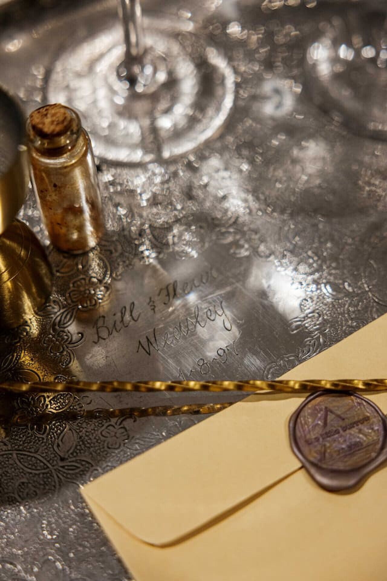 A vintage writing instrument, a wax seal, and an engraved metal surface with the inscription "Bill & Wendy."