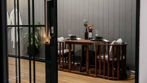 Un coin repas avec une table en bois, des chaises, un vase de fleurs et une bouteille de vin.