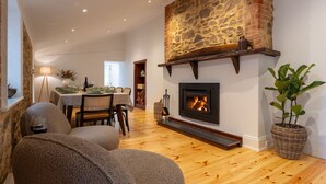 A cozy living room with a fireplace, a dining area, and a large plant.