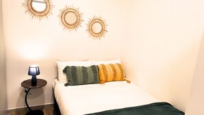 Un dormitorio con cama, almohadas, una lámpara y adornos en la pared.