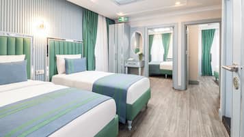 A hotel room with two beds, a vanity with a mirror, and a door leading to another room.