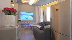 A living room with a TV, sofa, and a refrigerator. - Santa Rio Gold Taxim (Istanbul)