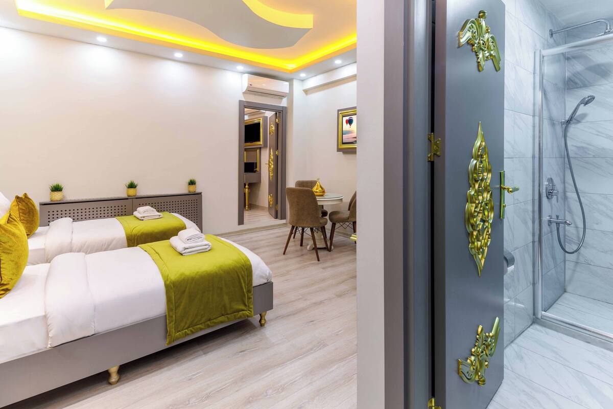 A modern hotel room with a bed, bedside tables, a desk, and a shower area.