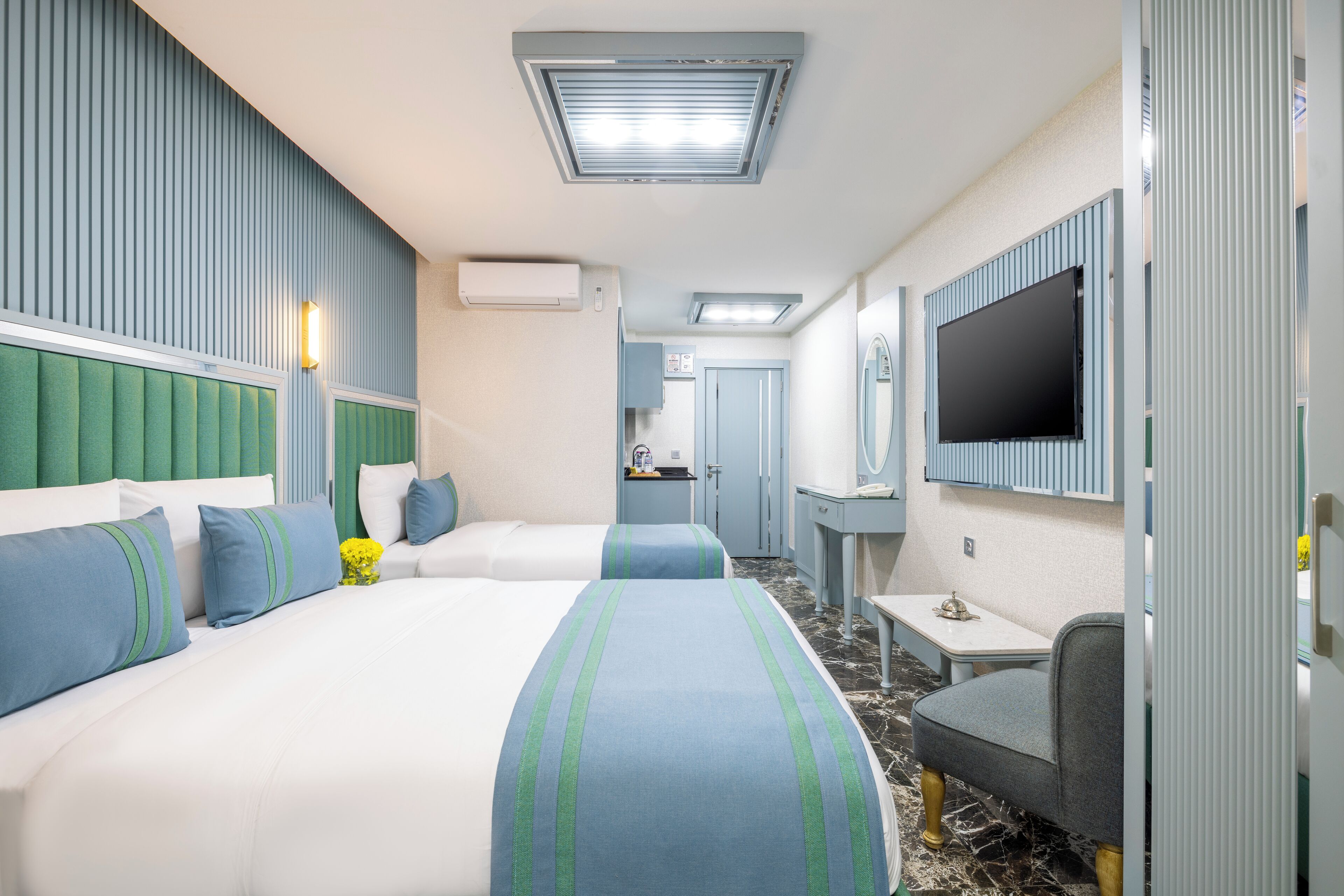 Een hotelkamer met twee bedden, een televisie, een bureau en een badkamer op de achtergrond.