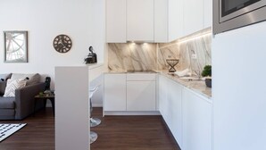 A modern kitchen with white cabinets, a marble backsplash, and a built-in oven. - Urban Views Duplex Apt Inspired by Casa da Música (Porto)