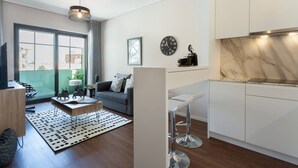 A modern living room with a sofa, coffee table, and a dining area with bar stools. There is a large window providing a view of the outside. - Urban Views Duplex Apt Inspired by Casa da Música (Porto)