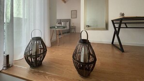 A modern bedroom with a wooden floor, a bed with white bedding, a bedside table, a mirror, and two decorative lanterns. - Urban Views Duplex Apt Inspired by Casa da Música (Porto)