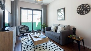 A modern living room with a grey sofa, a black and white patterned chair, a wooden coffee table, and a black and white rug. - Urban Views Duplex Apt Inspired by Casa da Música (Porto)