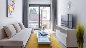 A modern living room with a sofa, coffee table, TV, and artwork.