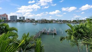 Un puerto deportivo con barcos amarrados, un muelle que se adentra en el agua y un horizonte urbano al fondo.
