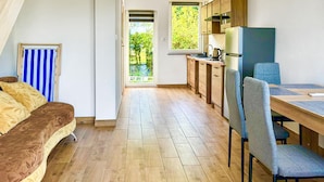 Una habitación acogedora con cama, una mesa de comedor con sillas, una zona de cocina y vistas al entorno verde.