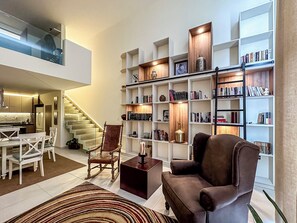 Un salon moderne avec un escalier, une bibliothèque et un coin repas.