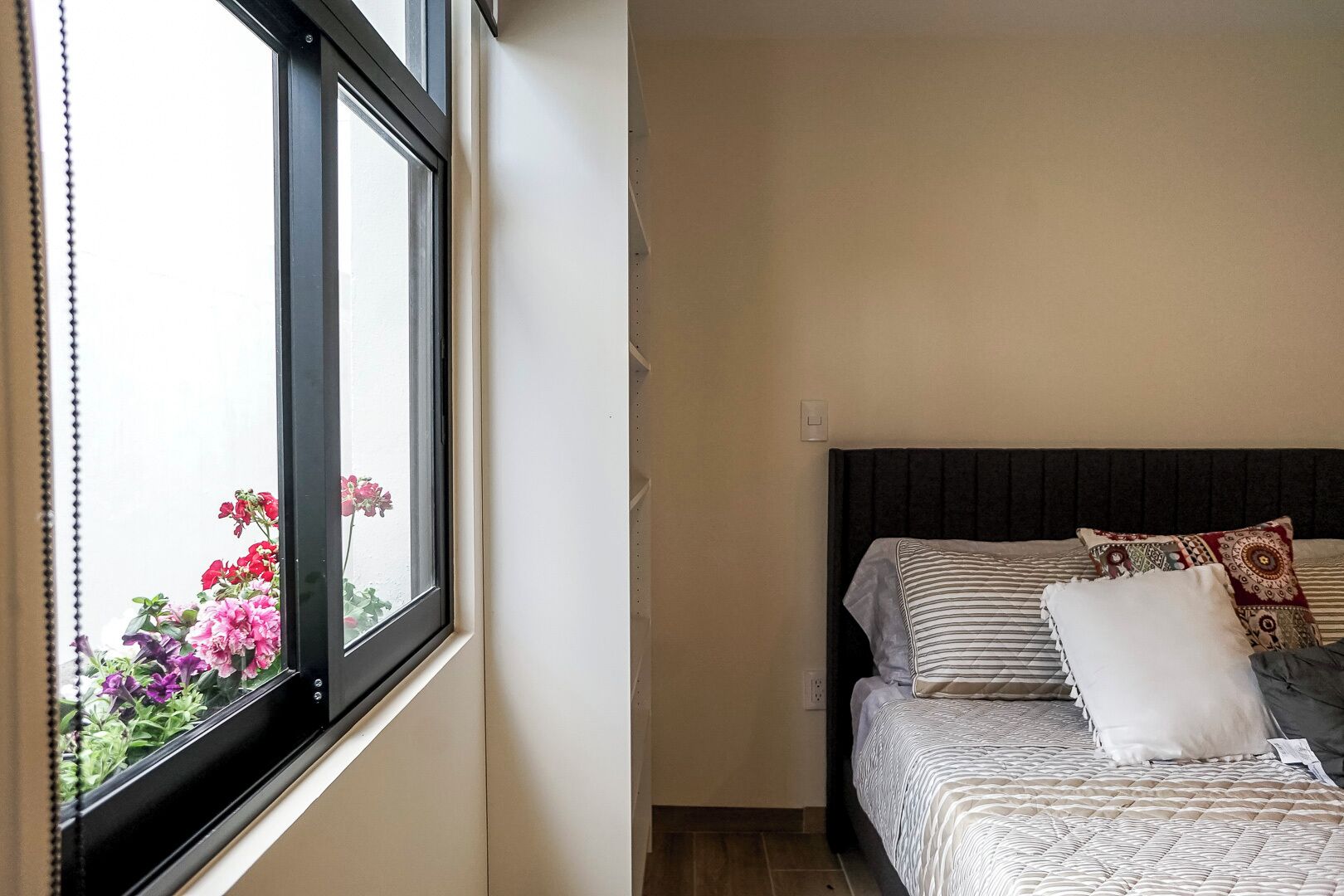 Una camera da letto con un letto, cuscini e una finestra fiorita.