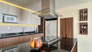 A modern kitchen with a microwave, stainless steel appliances, and a glass bowl with fruits on the counter.