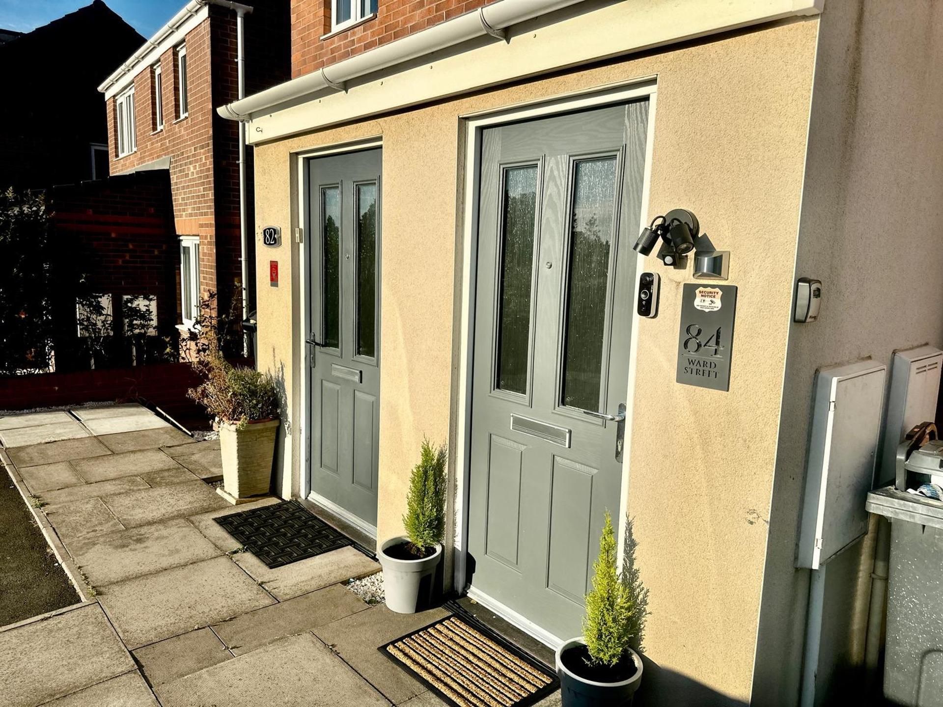 A residential building with two grey doors, a security notice, and a mailbox.