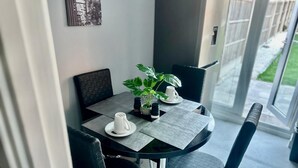 Un comedor moderno con una mesa de vidrio, sillas negras y una planta en maceta.