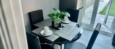 Un comedor moderno con una mesa de vidrio, sillas negras y una planta en maceta.