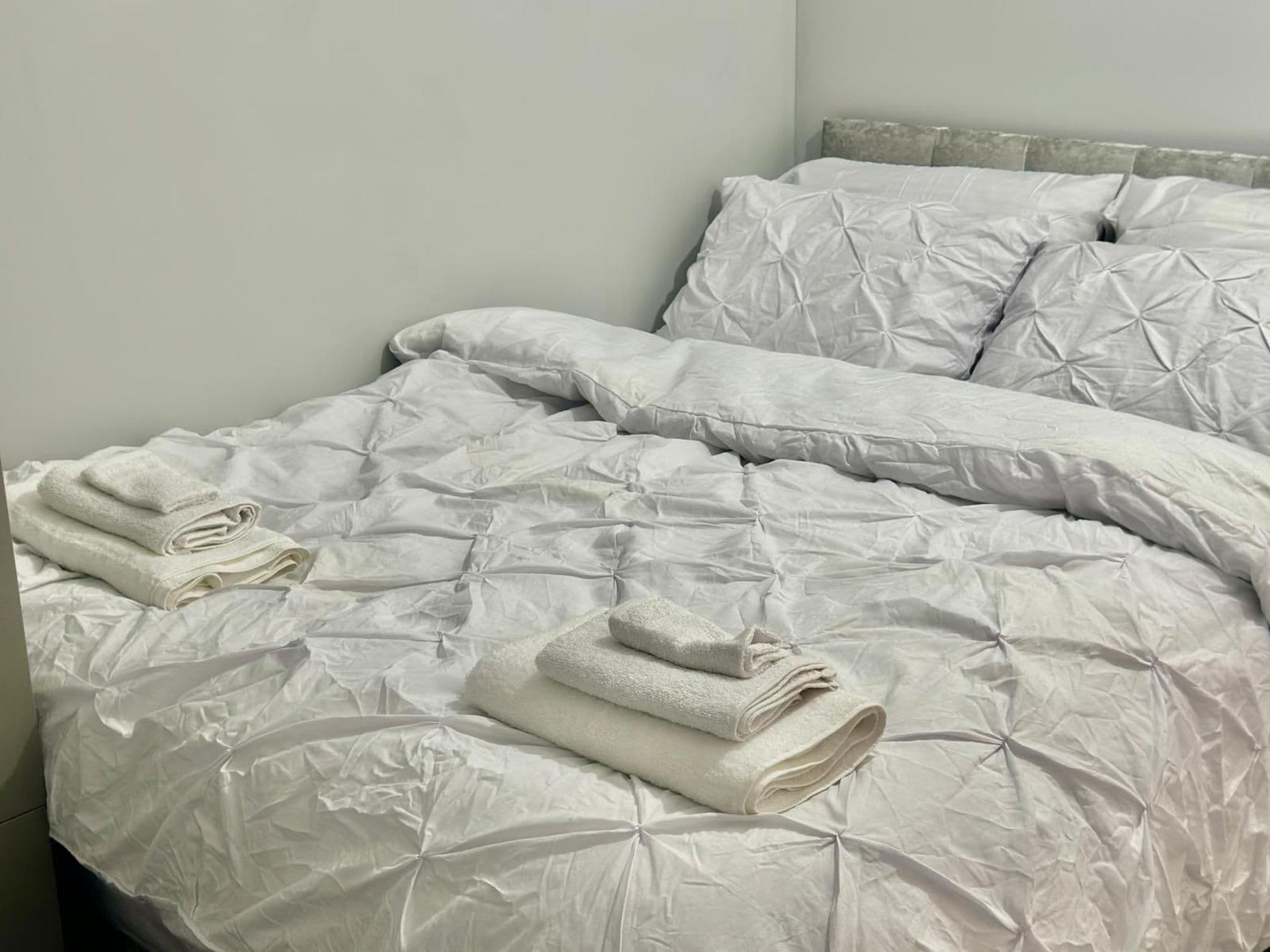 Un letto ben rifatto con un piumone e cuscini, e asciugamani piegati sul letto.