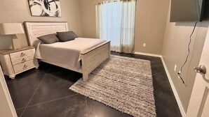 Quarto com cama, mesa de cabeceira e obra de arte na parede.