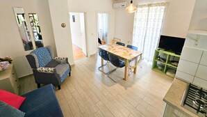 Una sala moderna con comedor, televisor y cocina equipada con estufa.