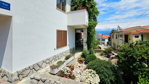 Un edificio blanco con base de piedra, una puerta de madera y un letrero que indica que es un apartamento.