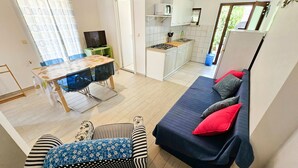 Un espacio habitable compacto con comedor, kitchenette y un sofá con cojines.