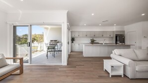 A modern kitchen with white cabinets, a dining area with a table and chairs, and a balcony with a sliding door.