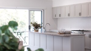 A modern kitchen with white cabinetry, a granite countertop, and a stainless steel sink.
