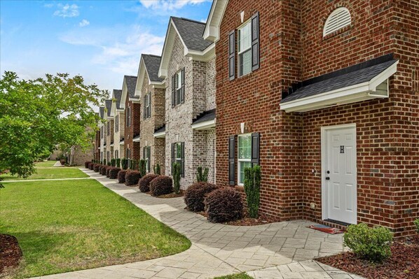 A row of townhouses with brick exteriors, white trim, and a well-maintained lawn. - Charming 3-bedroom townhome with Largest Accommodations in superb Florence (Florence)