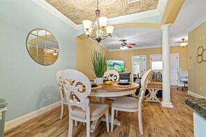 A dining area with a round wooden table, white upholstered chairs, a chandelier, and a ceiling fan. - Charming 3-bedroom townhome with Largest Accommodations in superb Florence (Florence)