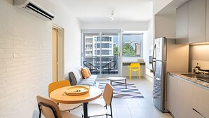 A modern apartment with a dining area, kitchen, and balcony. - Charming New Palermo Studio with Views (Buenos Aires)