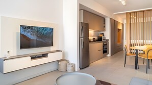 A modern kitchen with a built-in oven and refrigerator, a dining area with a wooden table and chairs, and a flat-screen TV mounted on the wall. - Charming New Palermo Studio with Views (Buenos Aires)