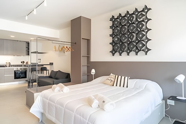 Relax in a spacious room with a large bed, desk, and kitchen area.
