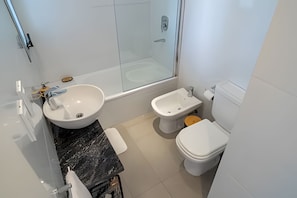 Features a large sink, toilet, bidet, and glass shower enclosure.
