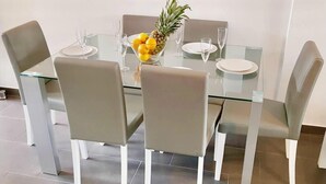 Un comedor moderno con una mesa de vidrio y sillas grises.