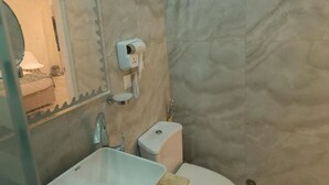 A bathroom with a sink, toilet, and a hairdryer mounted on the wall. - Maria Pyramids House - Standard Double or Twin Room (Giza City)