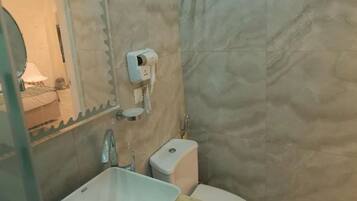 Une salle de bain équipée d’un lavabo, de toilettes et d’un sèche-cheveux fixé au mur.