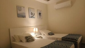 A hotel room with two beds, a nightstand with a lamp, and wall art. - Maria Pyramids House - Standard Double or Twin Room (Giza City)