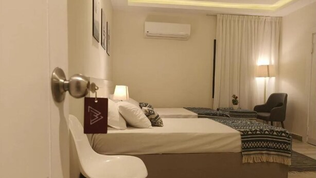 A hotel room with a bed, a chair, a desk, a lamp, and an air conditioning unit. - Maria Pyramids House - Standard Double or Twin Room (Giza City)