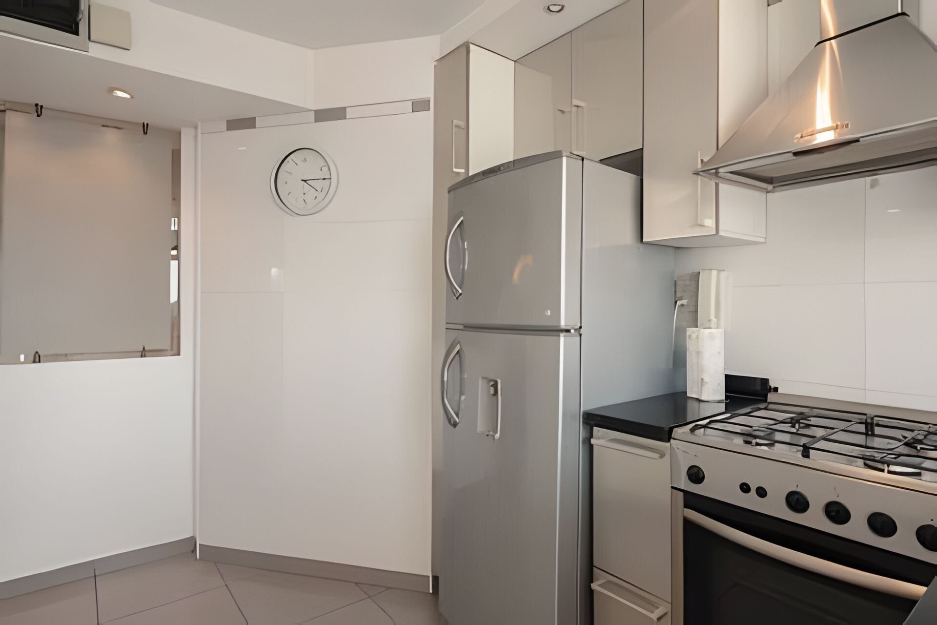 A modern kitchen with stainless steel appliances, a gas stove, and a wall clock.