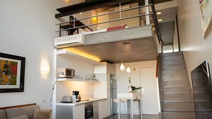 Un moderno apartamento tipo loft con entrepiso, cocina, comedor y escalera.