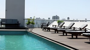 Zona de piscina en la azotea con sillones de descanso y un espacio para sentarse.
