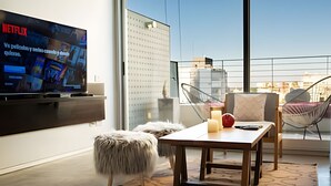 Una sala de estar moderna con un televisor de pantalla plana, una mesa de madera y una silla de vidrio.