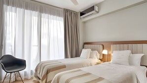 Une chambre d’hôtel avec deux lits, une chaise et un ventilateur de plafond.