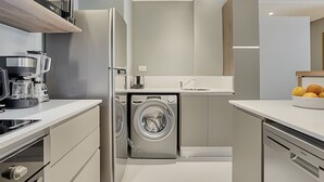 Une cuisine moderne équipée d’un lave-linge, d’une machine à café et d’un panier à fruits.