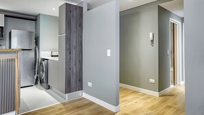 Une cuisine moderne dotée d’un réfrigérateur encastré, d’un mur d’accent en bois et d’un couloir gris menant à une porte.